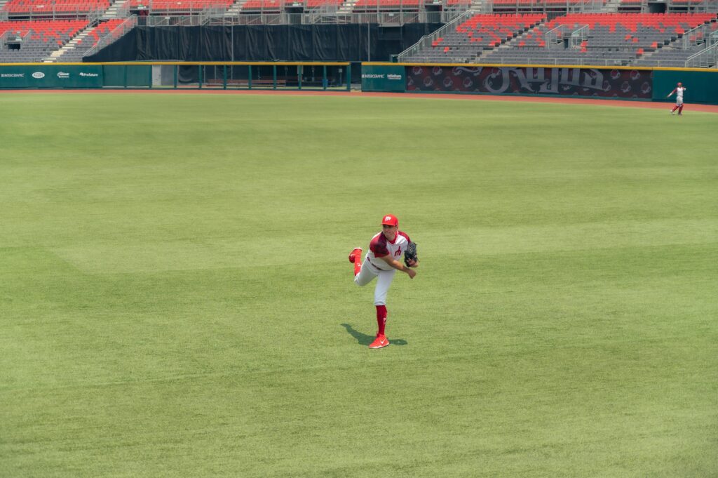A baseball player pitching on a grass field in an empty stadium.