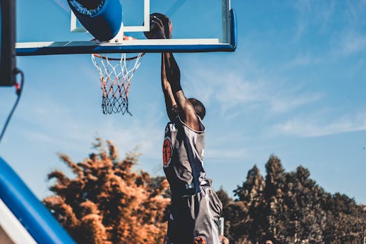 High-energy basketball dunk captured outdoors during daytime play.