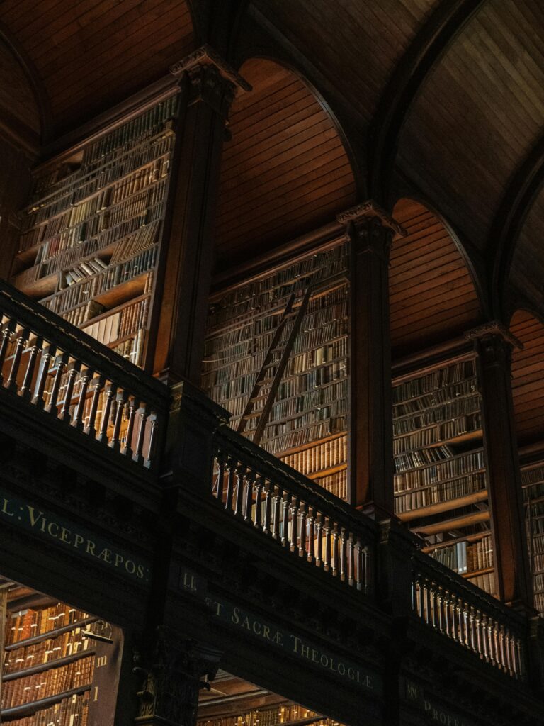 Interior view of the historic Trinity College Library in Dublin, showcasing its ornate wooden shelves filled with books.