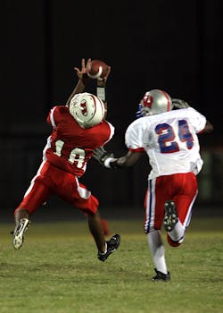 Maxx Crosby Trade Details and Implications Dynamic shot of two football players in action during a night game, showcasing athletic skills.