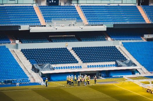 Bears Stadium Ramblings Intensify A wide-angle view of a stadium seating area in Madrid with visible workers and vibrant blue seats.