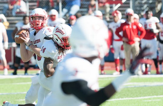 Quarterbacks: Show me the Money (and the Wins) Football players on the field captured in action during a lively game.