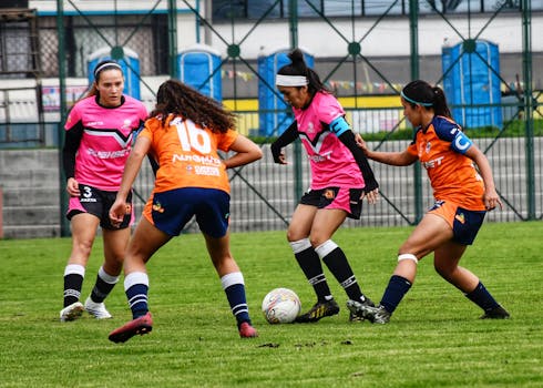 Female soccer players in action on a grassy field, showcasing teamwork and athleticism.