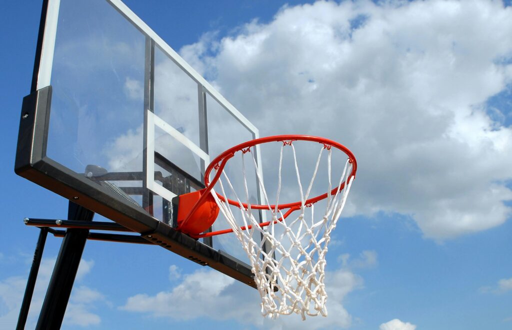 A basketball hoop and backboard set against a clear blue sky, capturing the essence of outdoor sports.