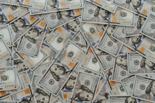 US hundred dollar bills scattered in abundance creating a financial backdrop.