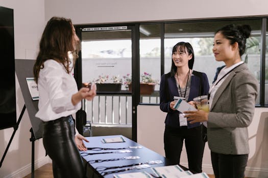 Businesswomen registering at a conference desk, smiling and interacting in a professional setting.