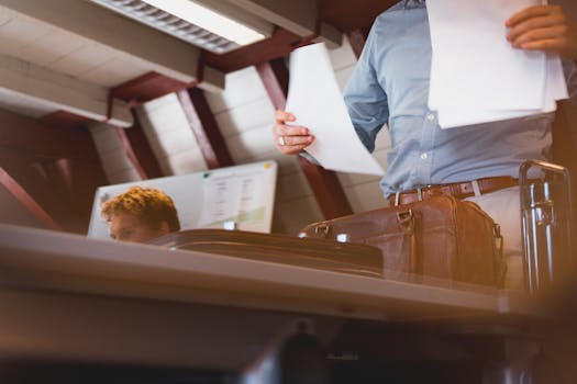 A businessman reviews documents with a leather bag in an office setting.