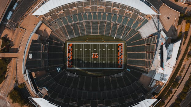 From above drone view of empty American football stadium with white lines and emblem on sunny day