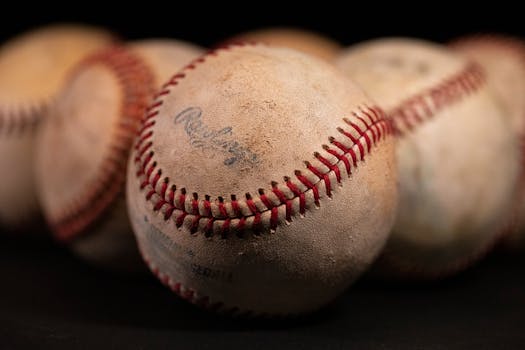Focused close-up of old baseballs with visible stitching and texture against a dark background.